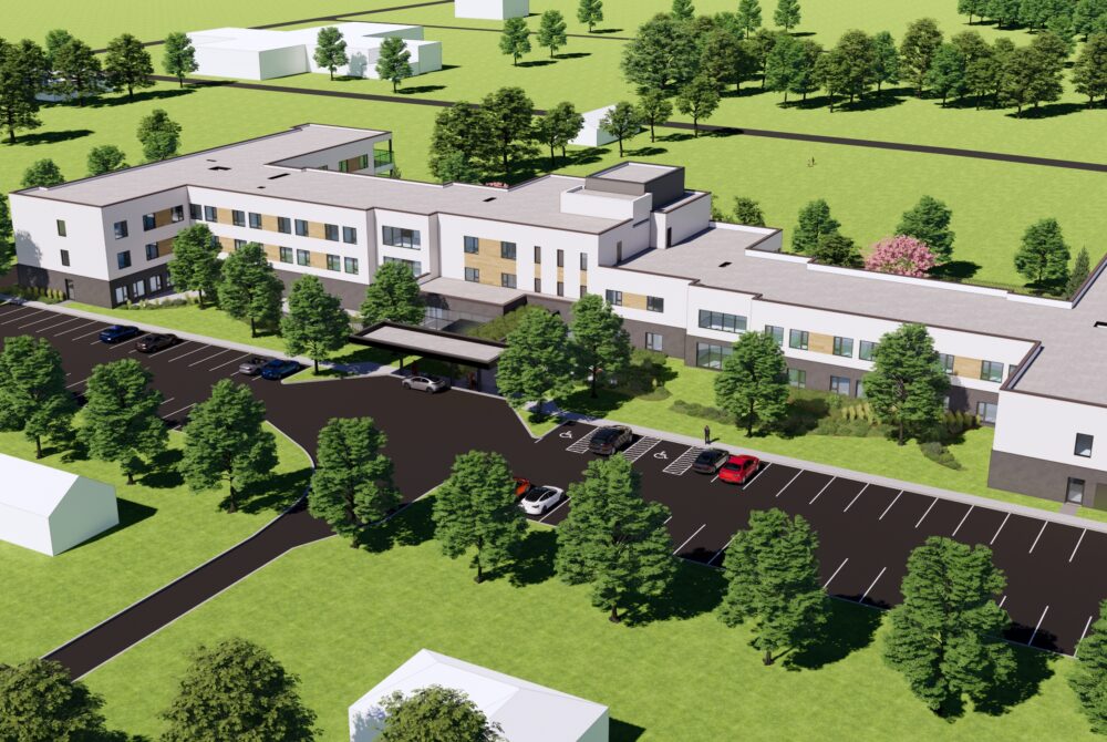 Aerial rendering of a low-rise long-term care home with parking areas, landscaped grounds, and surrounding trees in a rural setting.